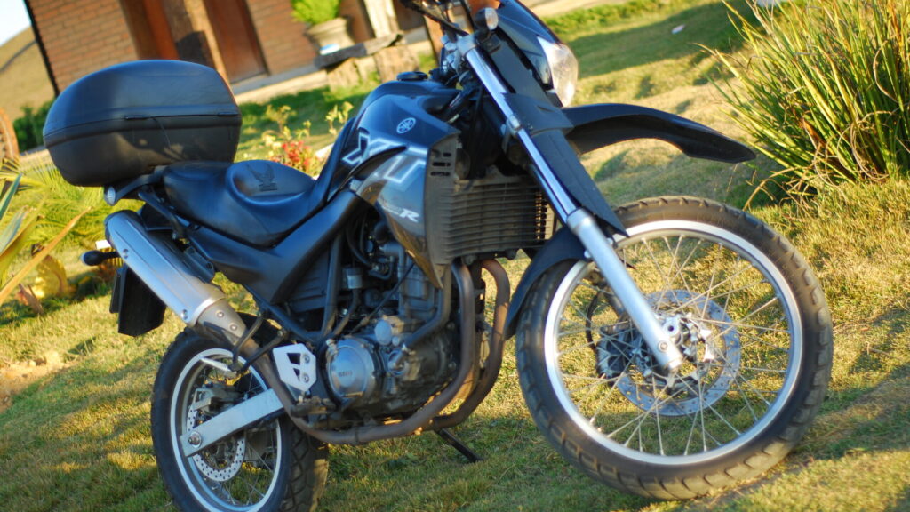 Yamaha XT 660: a trail que recusa aposentadoria Yamaha XT 660 R preta vista de perfil, com baú traseiro, motor monocilíndrico e rodas raiadas aro grande