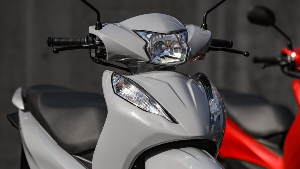 Honda Biz 125: por que ela nunca sai de linha Detalhe do farol dianteiro e guidão da Honda Biz 125 na cor branca