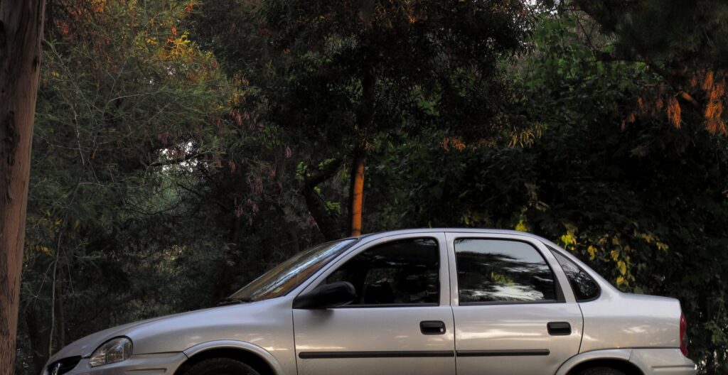 Corsa Classic: o carro que a Chevrolet não conseguiu matar Chevrolet Corsa Classic sedã branco visto de perfil lateral em rua com árvores