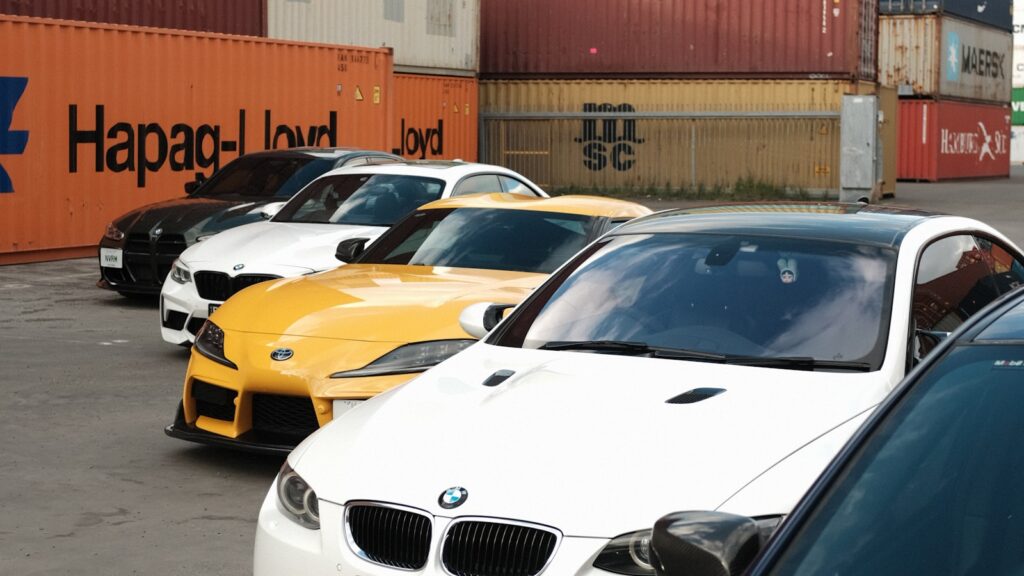 Brasil assume topo mundial em compra de carros chineses Carros novos estacionados em pátio portuário diante de contêineres de navios cargueiros