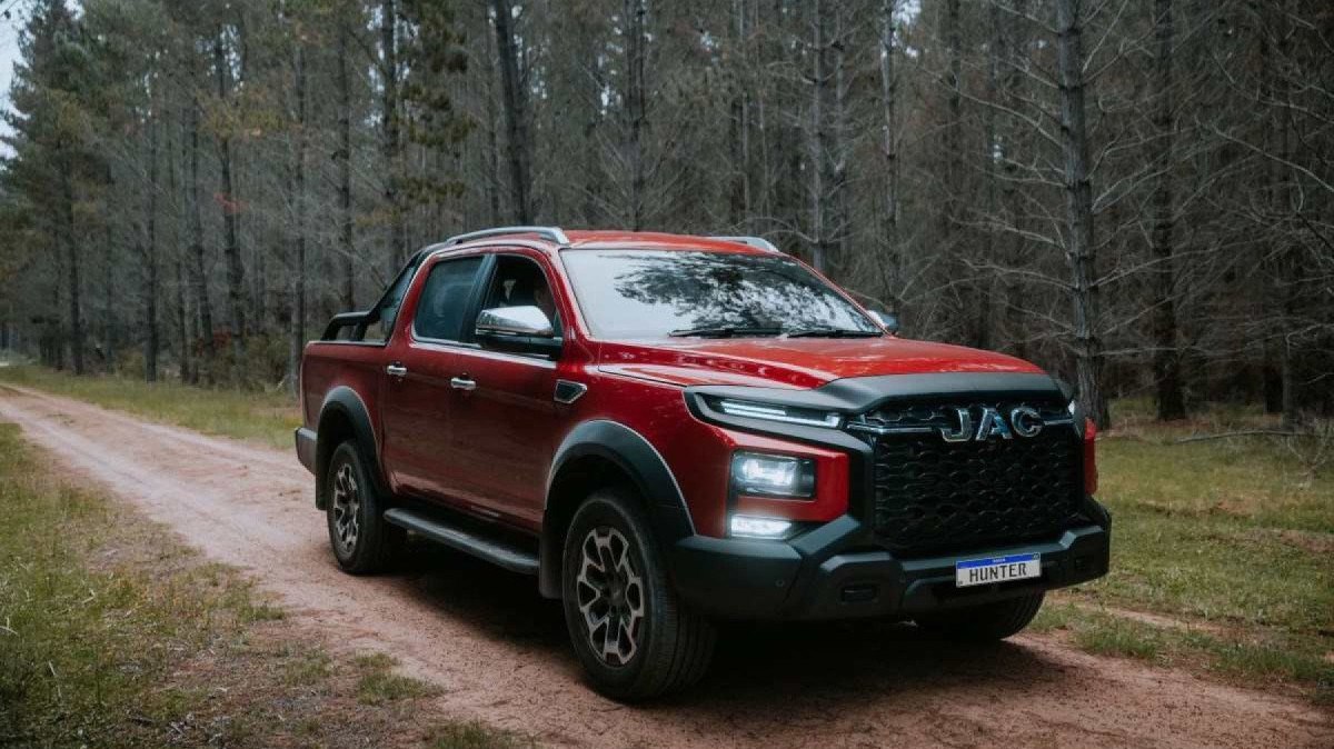 JAC Motors: 85 elétricos e rede menor no Brasil Interior de um JAC elétrico com painel digital e central multimídia, detalhe horizontal mostrando acabamento e comandos do veículo