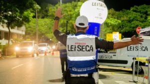Blitz da Lei Seca em avenida brasileira à noite, agentes abordando carros e utilizando etilômetro, fotografia horizontal