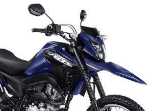 Honda CG 160 preta em foto frontal horizontal, ao lado de uma Honda Biz em ambiente urbano brasileiro