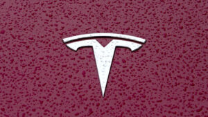Tesla Model 3 e Tesla Model Y em vista frontal, estacionados diante de um centro de atendimento na China, orientação horizontal