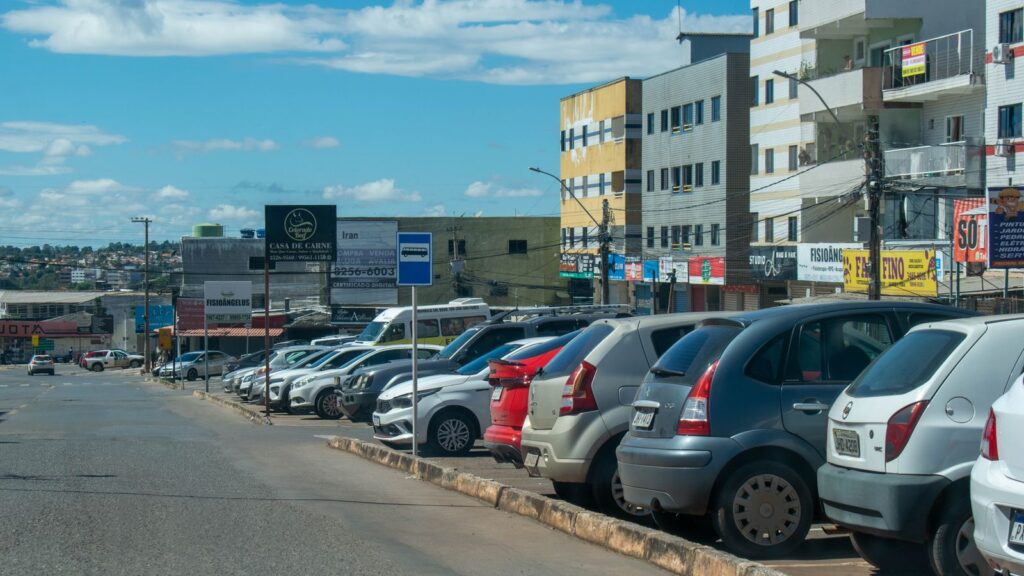 Carros populares estacionados em rua brasileira, veículos sujeitos a IPVA e licenciamento