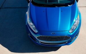 Ford EcoBoost: Correia pode afetar 135 mil carros? Motor Ford 1.0 EcoBoost em bancada de oficina, com destaque para a correia dentada banhada a óleo, orientação horizontal