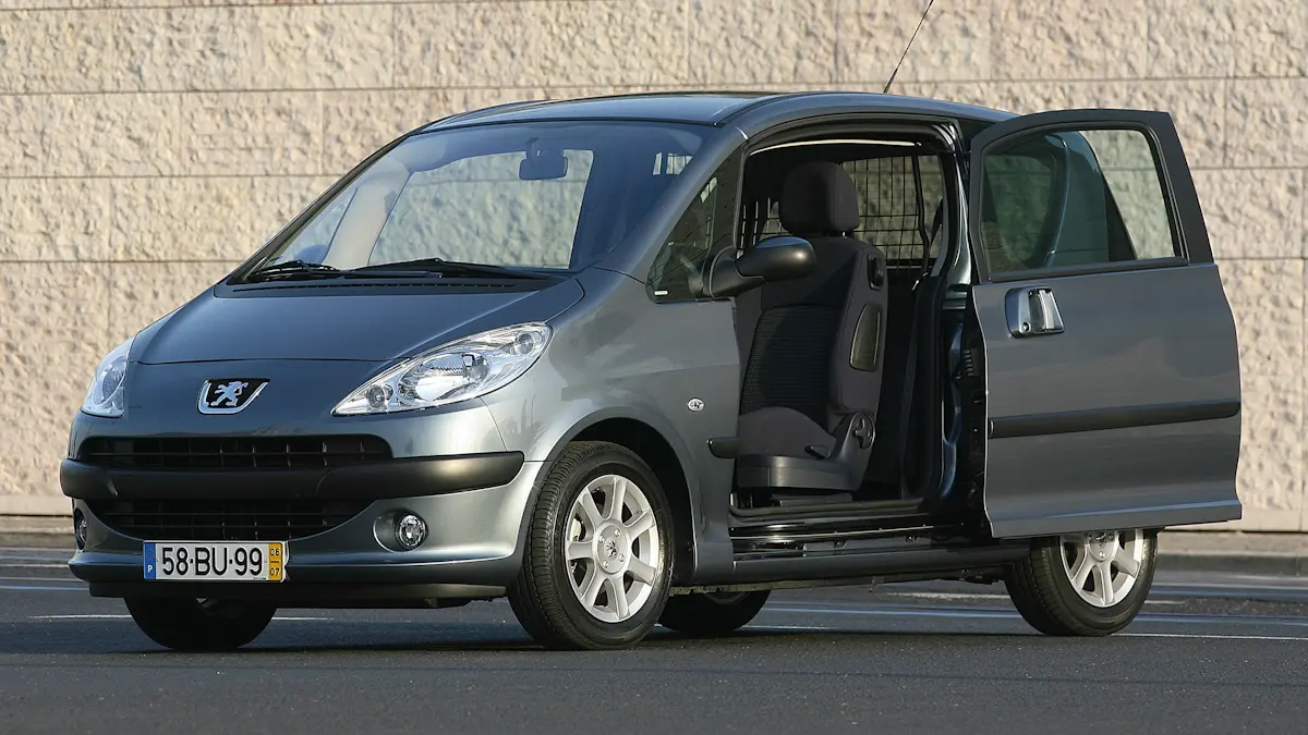 Peugeot 1007 prata em vista lateral, mostrando claramente as duas portas corrediças abertas, estacionamento urbano europeu, orientação horizontal landscape