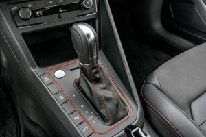 motorista selecionando D em um câmbio automático, painel do carro aceso e interior em orientação horizontal, landscape