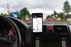 Tela do Waze no painel de um carro exibindo alerta de área escolar em rodovia federal brasileira, interface em português, foto horizontal