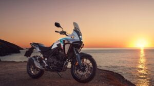 Honda NX500 2026 na cor branca parada em mirante durante o pôr do sol