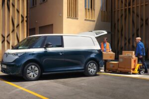 ID. Buzz Cargo: Bateria menor realmente roda mais? Volkswagen ID. Buzz elétrica branca em vista frontal, estacionada diante de uma concessionária brasileira, fotografia horizontal landscape