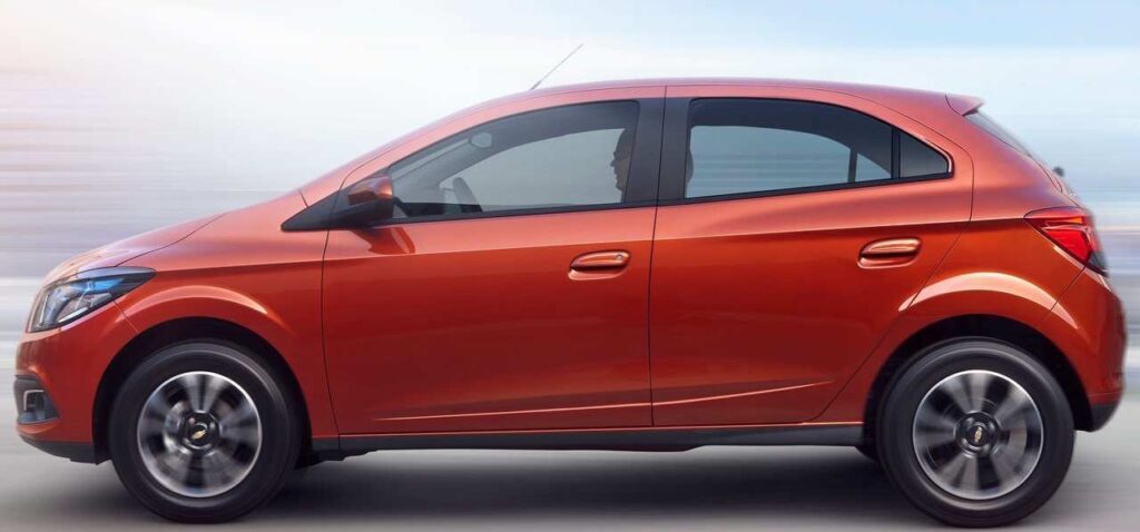 Chevrolet Onix 2013 de primeira geração laranja em vista lateral