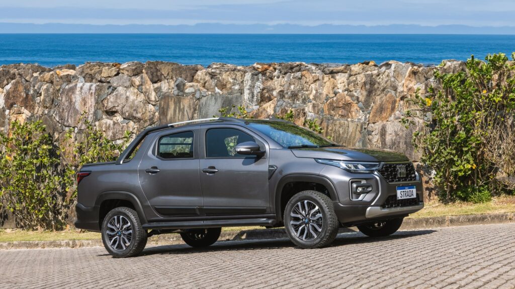 Strada usada: qual versão da segunda geração comprar sem susto? Fiat Strada Ranch cinza de cabine dupla em vista lateral com o mar ao fundo