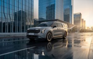 Kia Carnival HEV cinza em movimento, vista frontal em avenida com edifícios