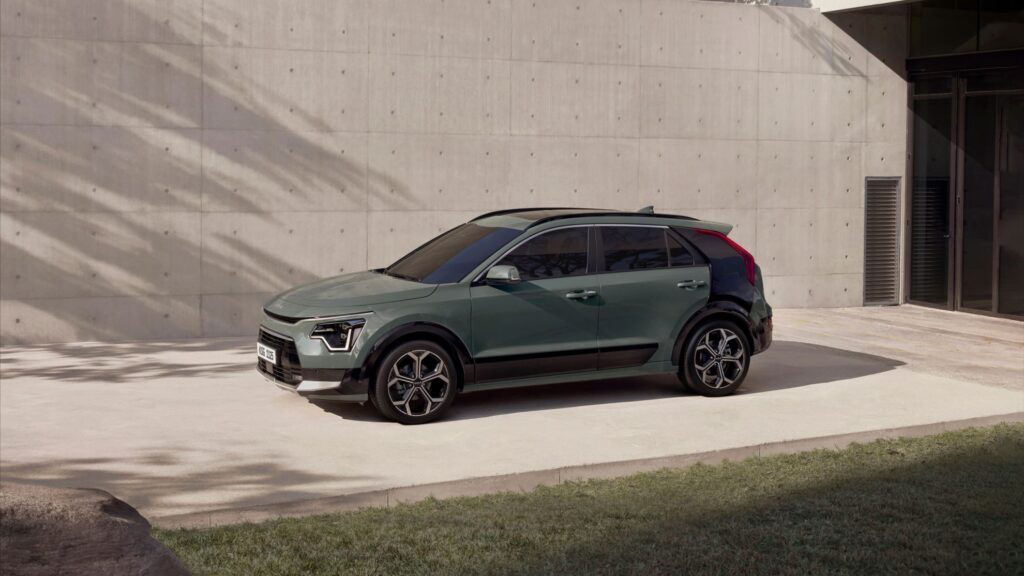 Kia Niro HEV verde, vista lateral em perspectiva diante de muro de concreto